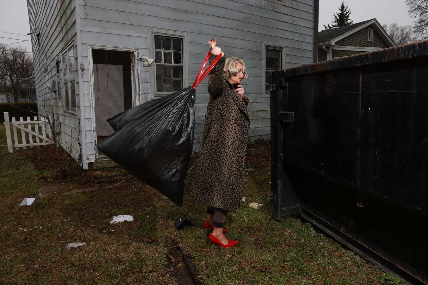 Person in winter clothing slips and falls on an icy walkway while walking towards a house entrance.