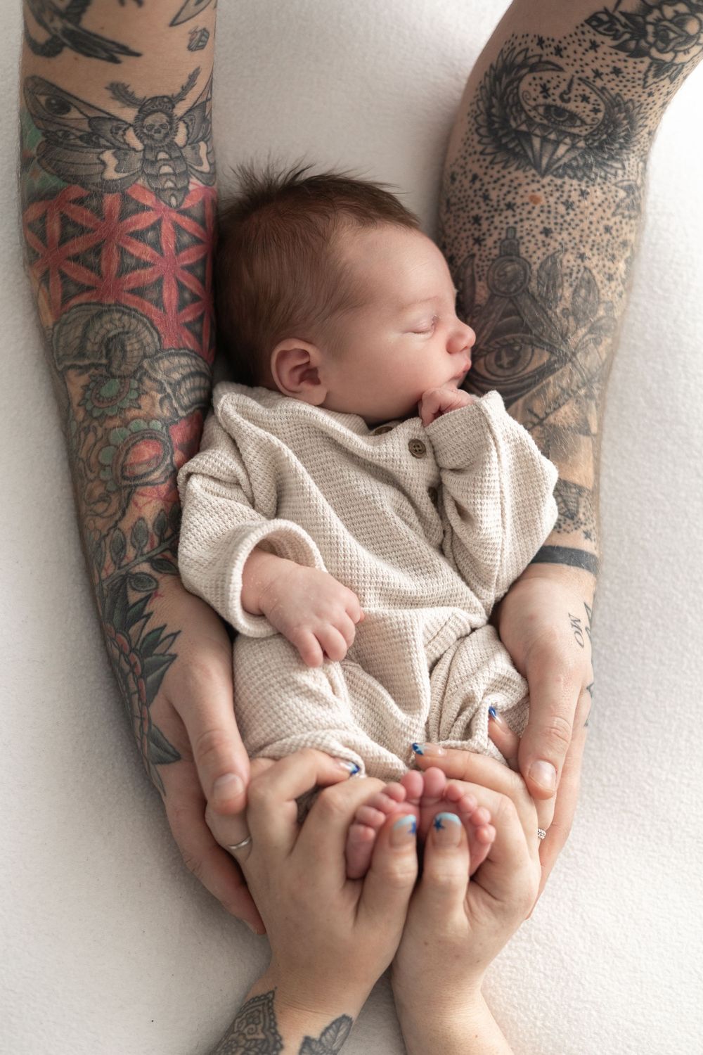 Newborn baby sleeping peacefully in parent's arms, cradled gently in hands newborn photographer Nottingham cosy home studio