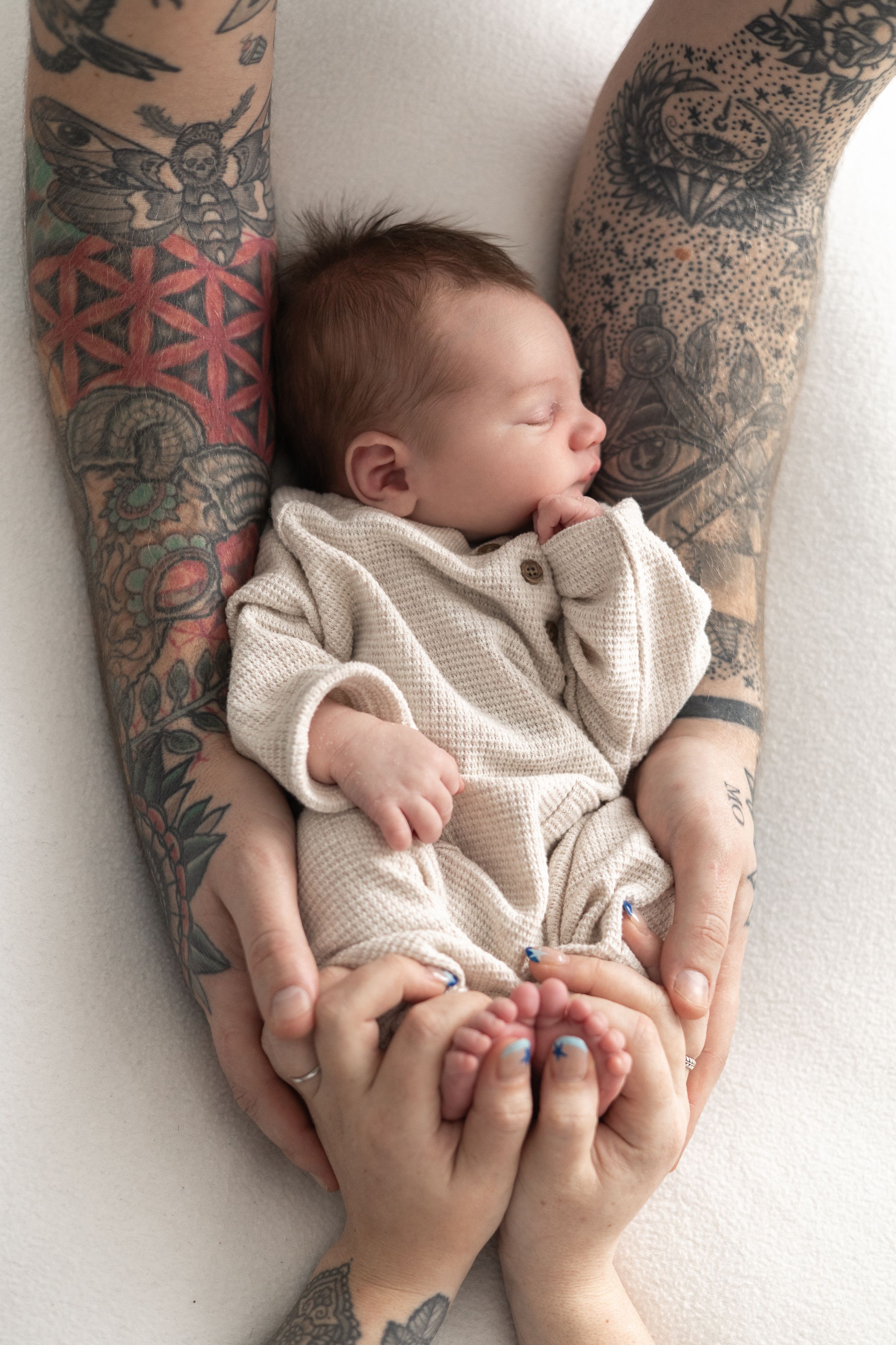 Newborn baby sleeping peacefully in parent's arms, cradled gently in hands newborn photographer Nottingham cosy home studio