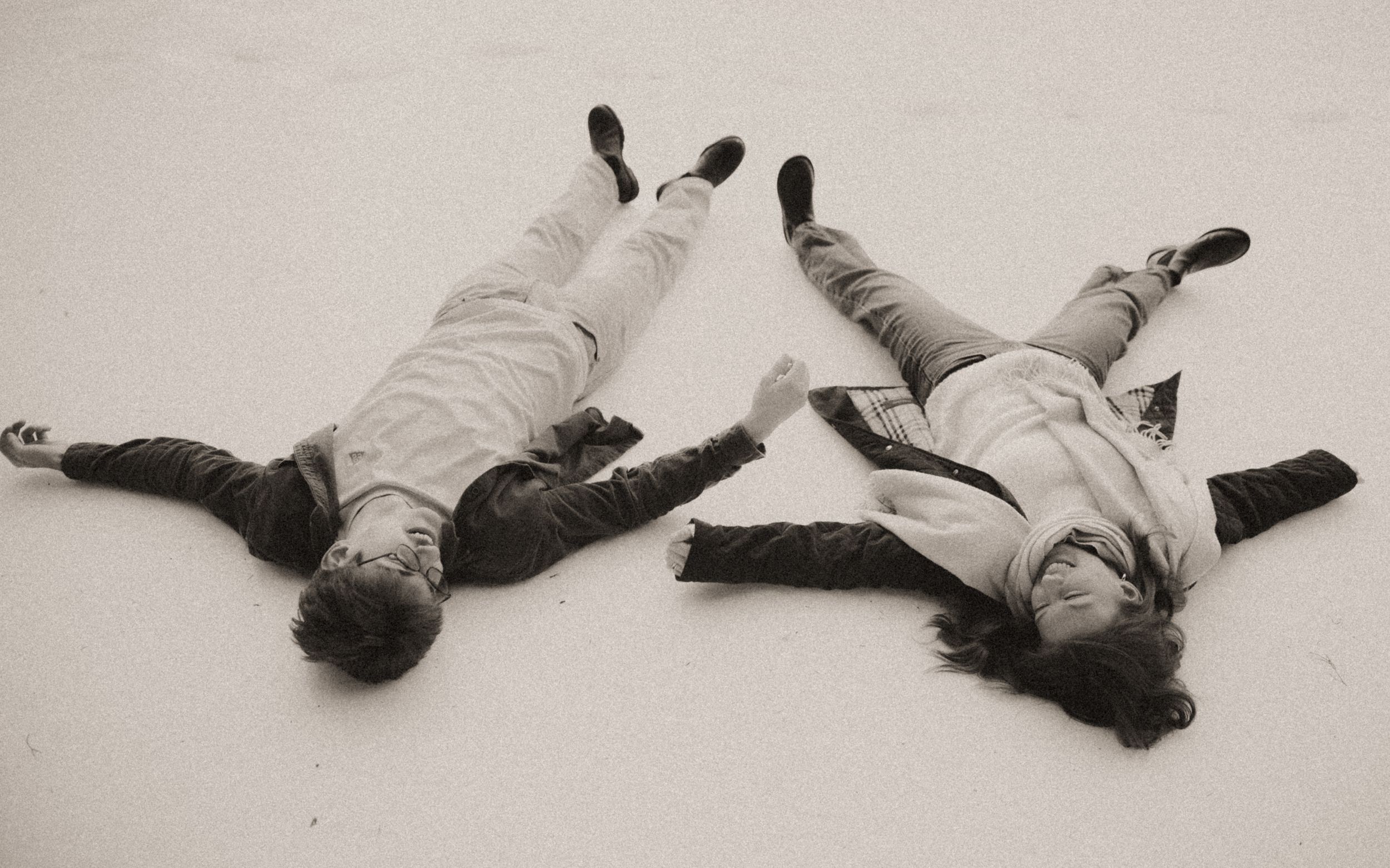 A series of black and white photographs showing figures making snow angels in a progressive sequence.