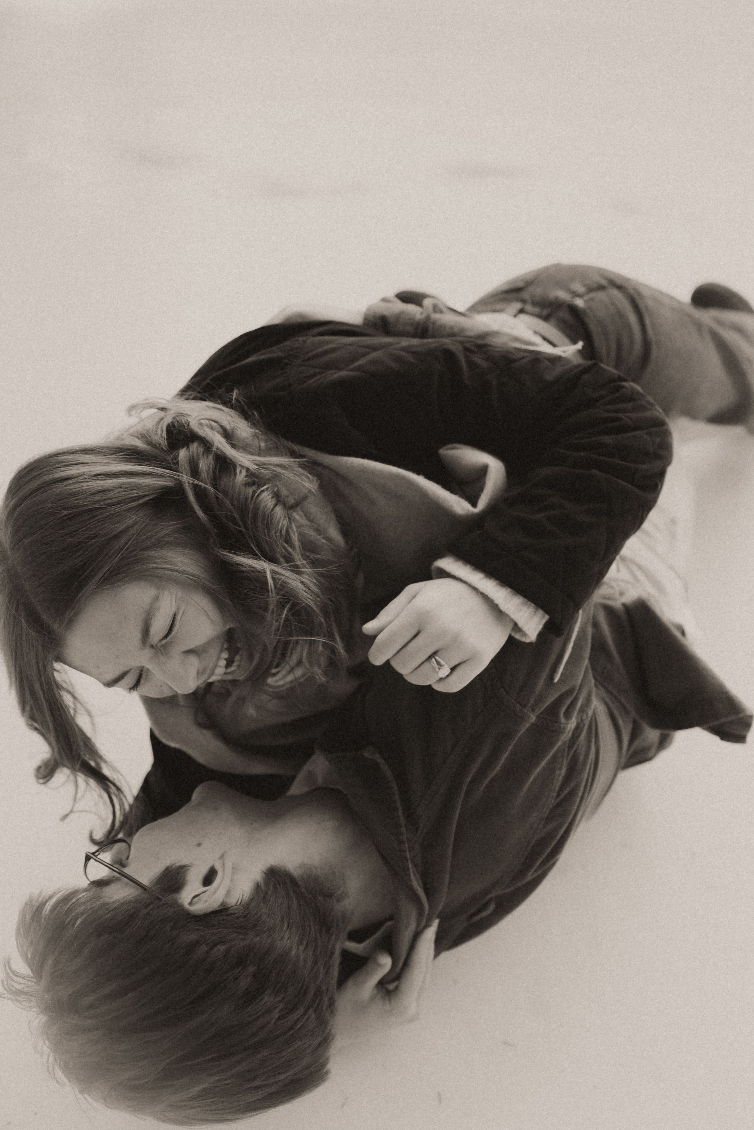 Black and white artistic portrait series showing someone lying down in a dark sweater against a light background.