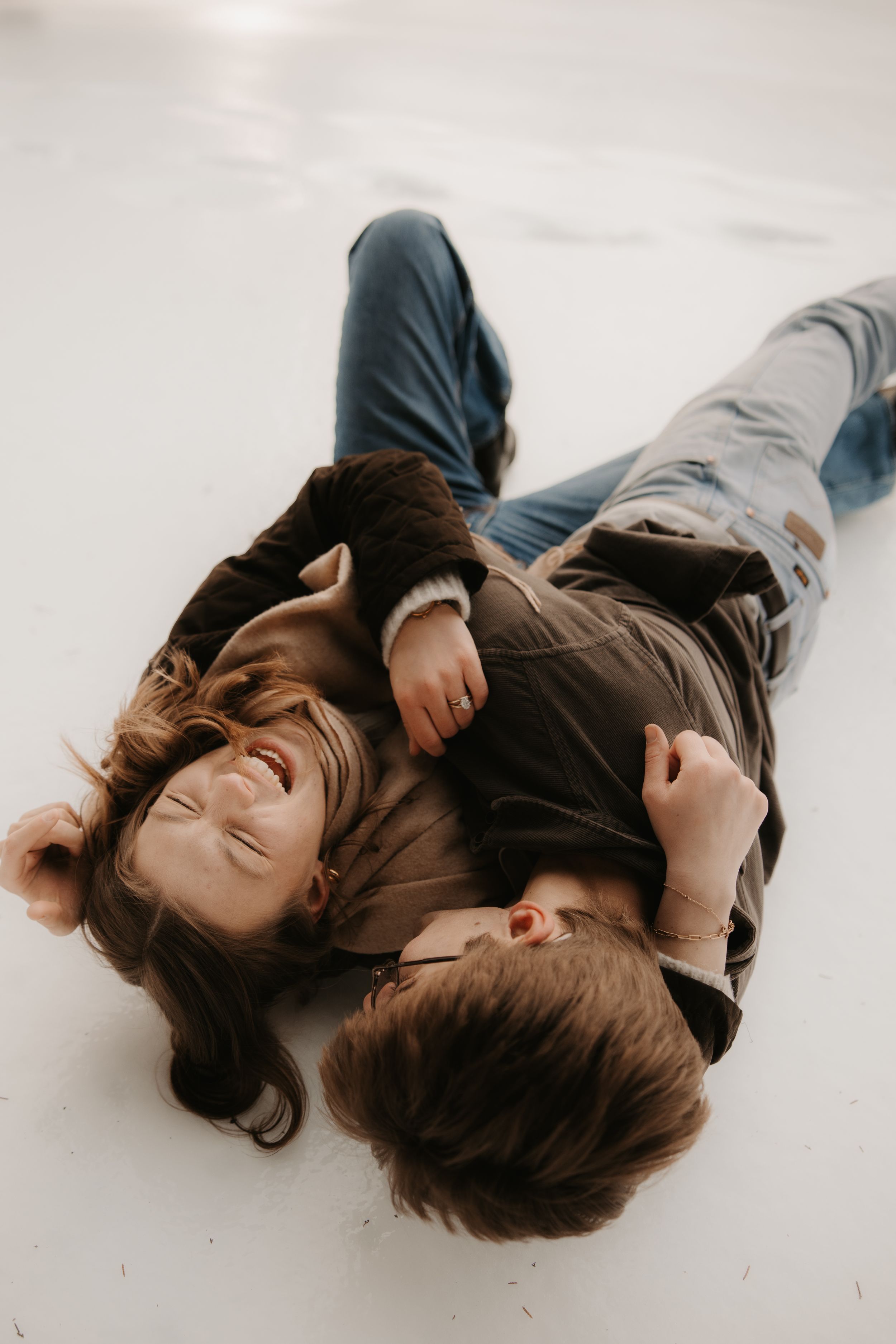 A sequence of five photos showing two people lying on a white floor in casual clothing.