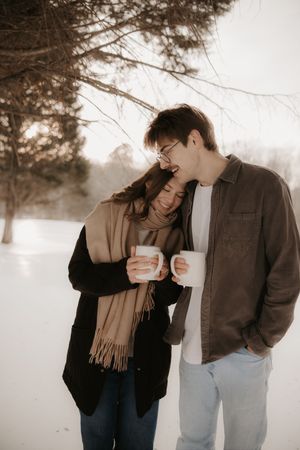Sepia toned winter scene of couple laughing together outdoors in warm clothing.