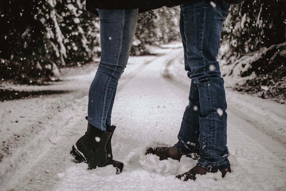 Close-up of snow-covered boots and jeans on a snowy winter path.