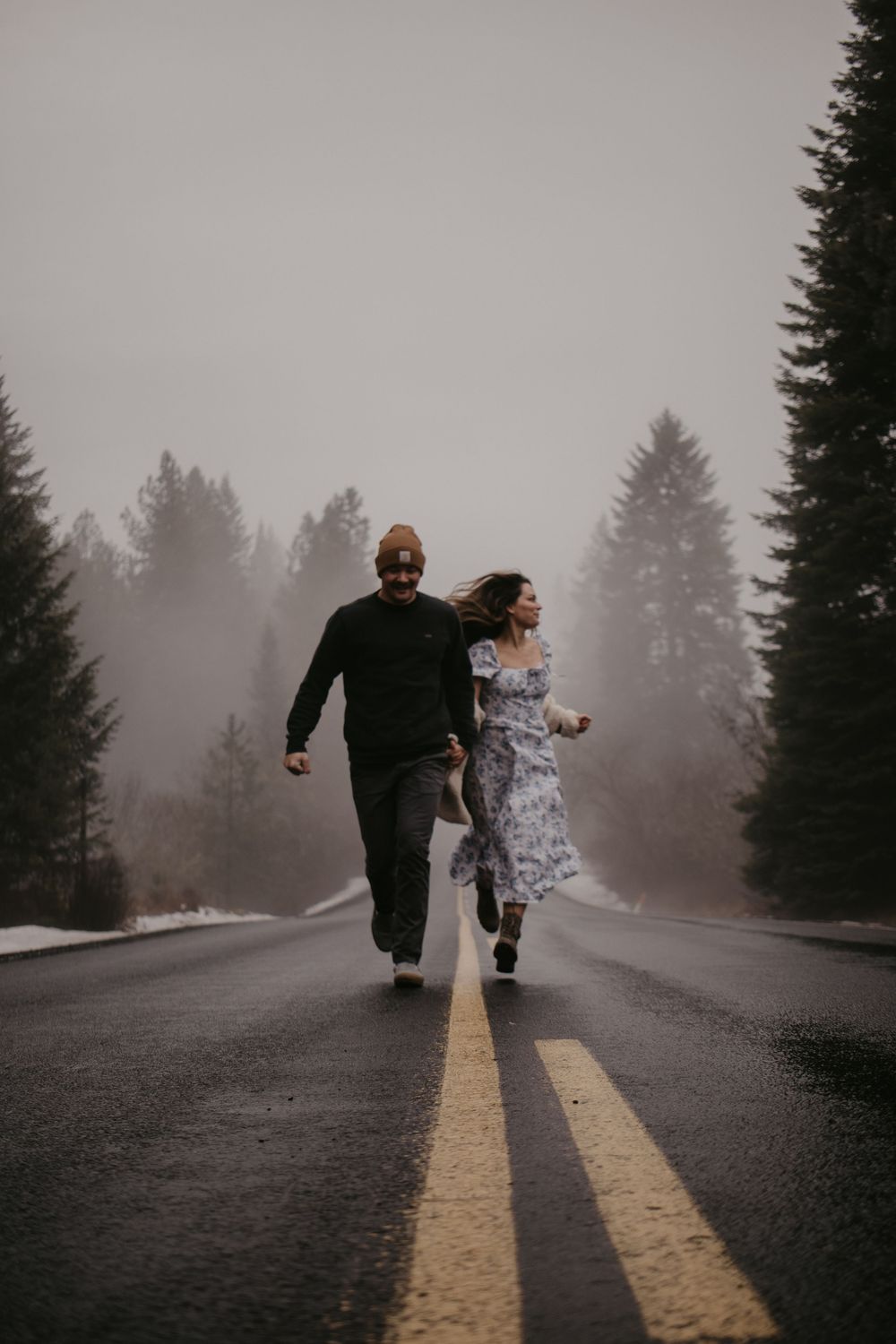 Couple running together on misty forest road in winter.