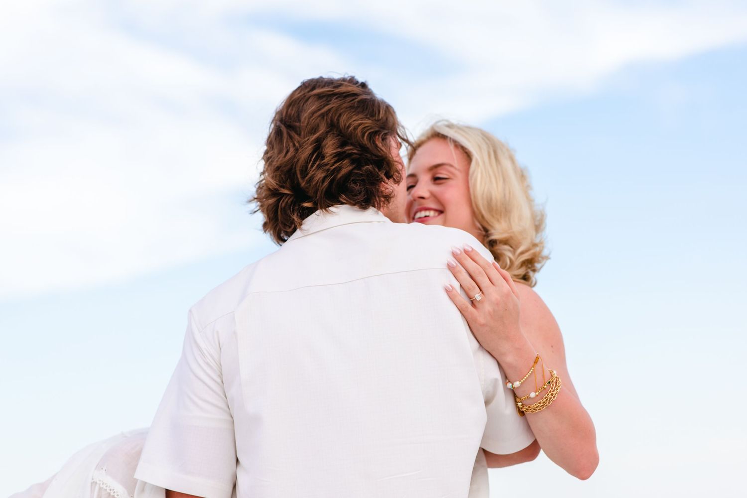 A series of four romantic beach photos showing couples embracing against a bright blue sky and ocean background.
