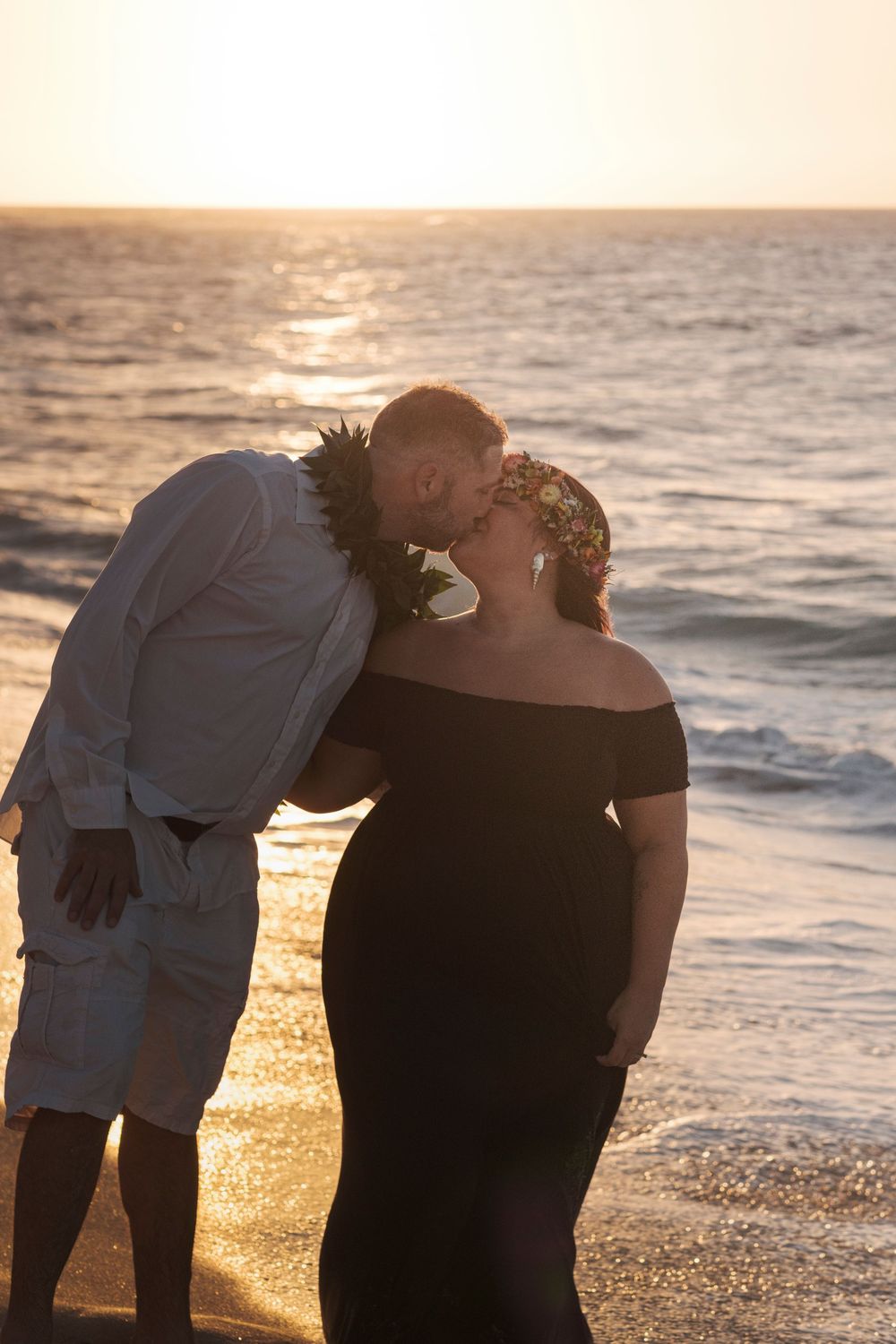Romantic silhouette of a couple kissing during a North Shore Oahu beach photography session at golden sunset.