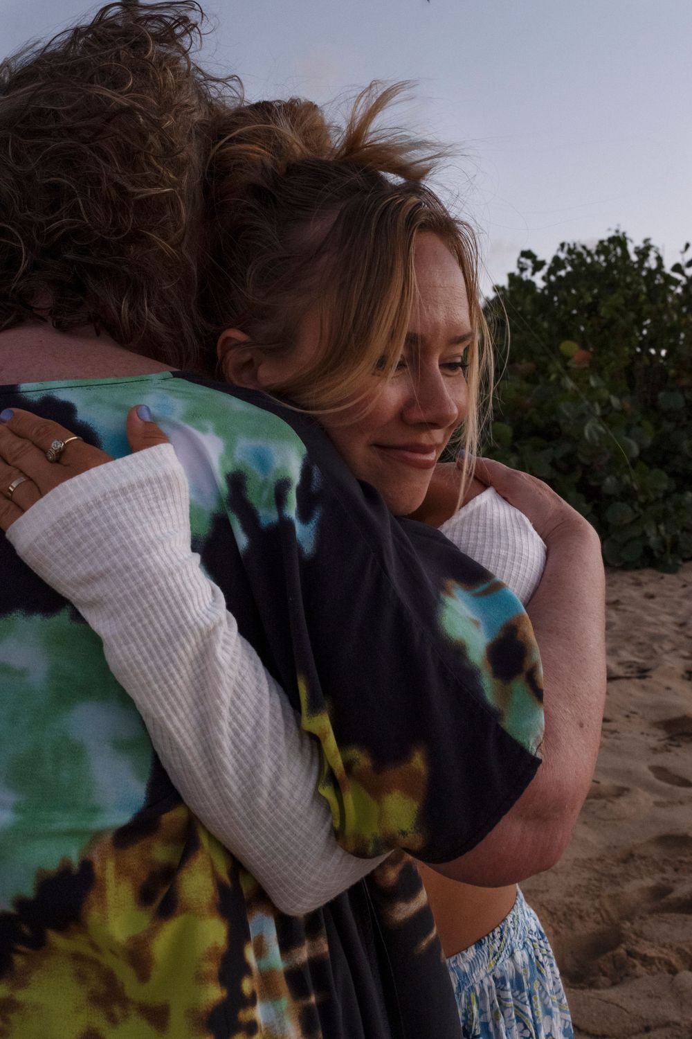Mother and daughter hug together during a candid North Shore Oahu family photography session at sunset.