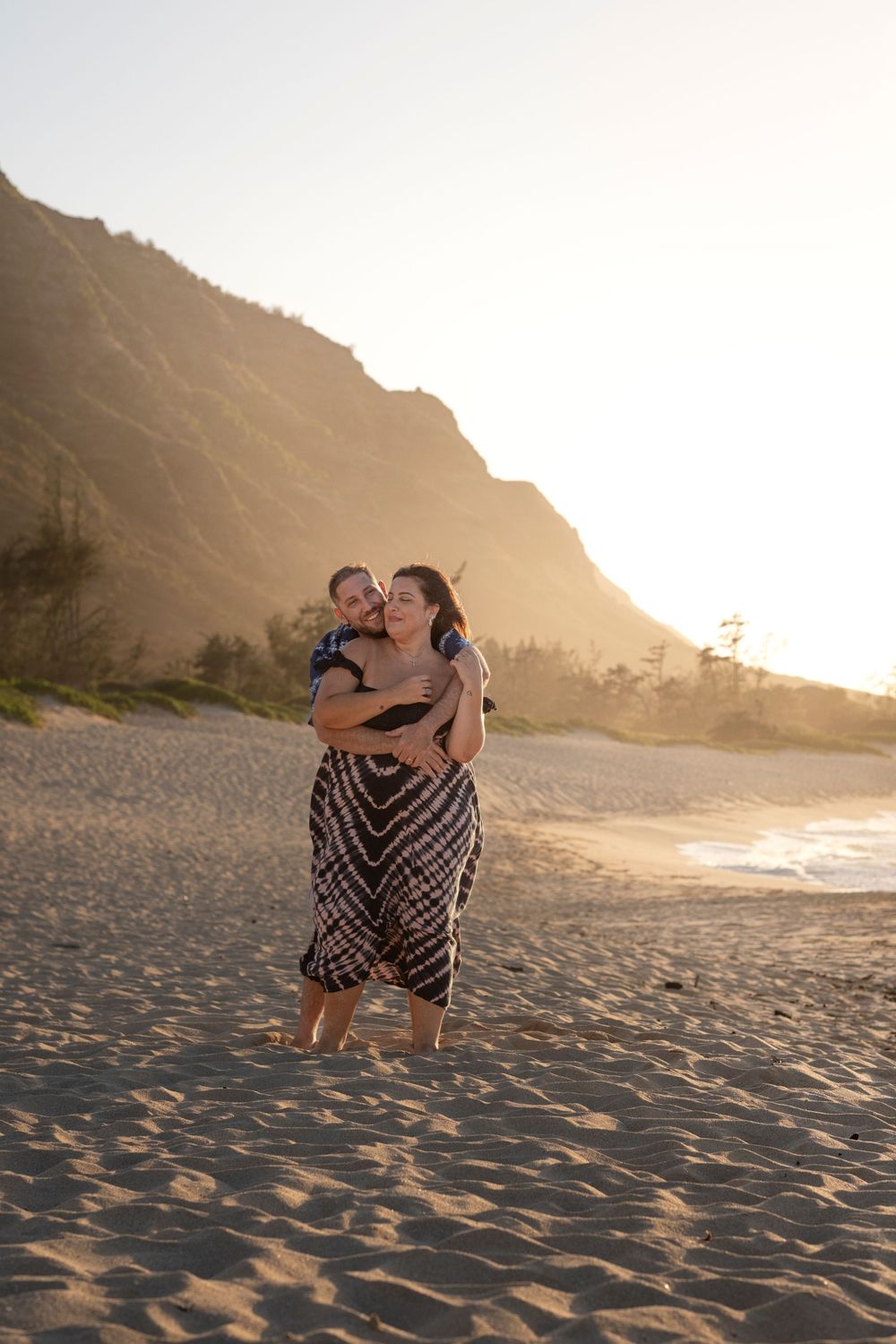 Couple laughing and embracing during a North Shore Oahu couples photography session on a scenic beach at sunset.