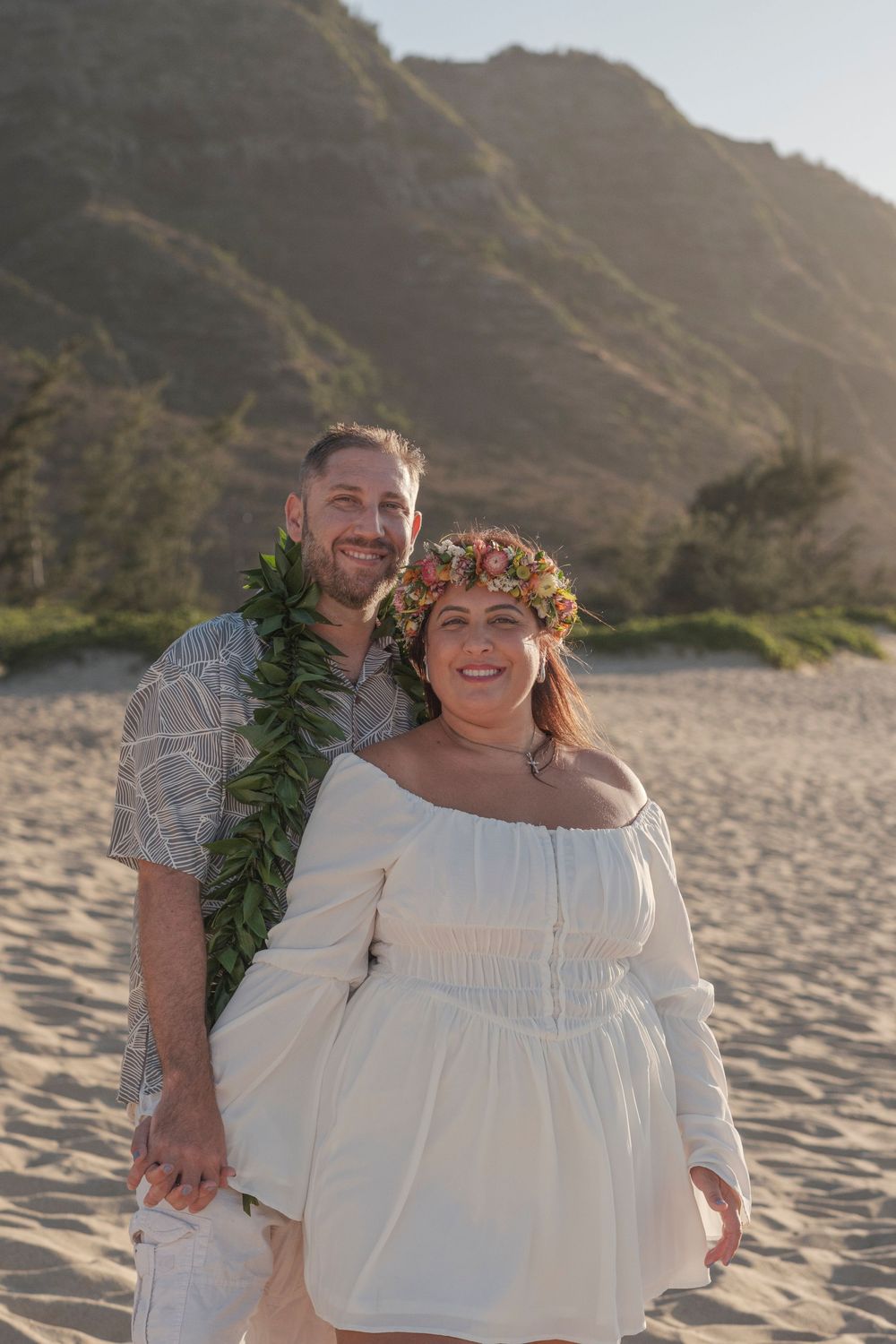 Couple wearing Hawaiian wedding leis during a North Shore Oahu beach wedding photography session at sunset.