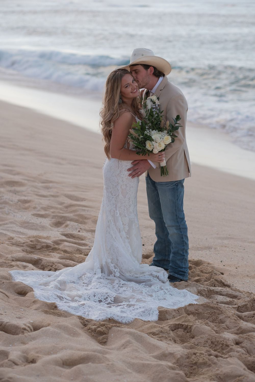 A couple embraces on a sandy beach during a romantic photoshoot on Oahu North Shore