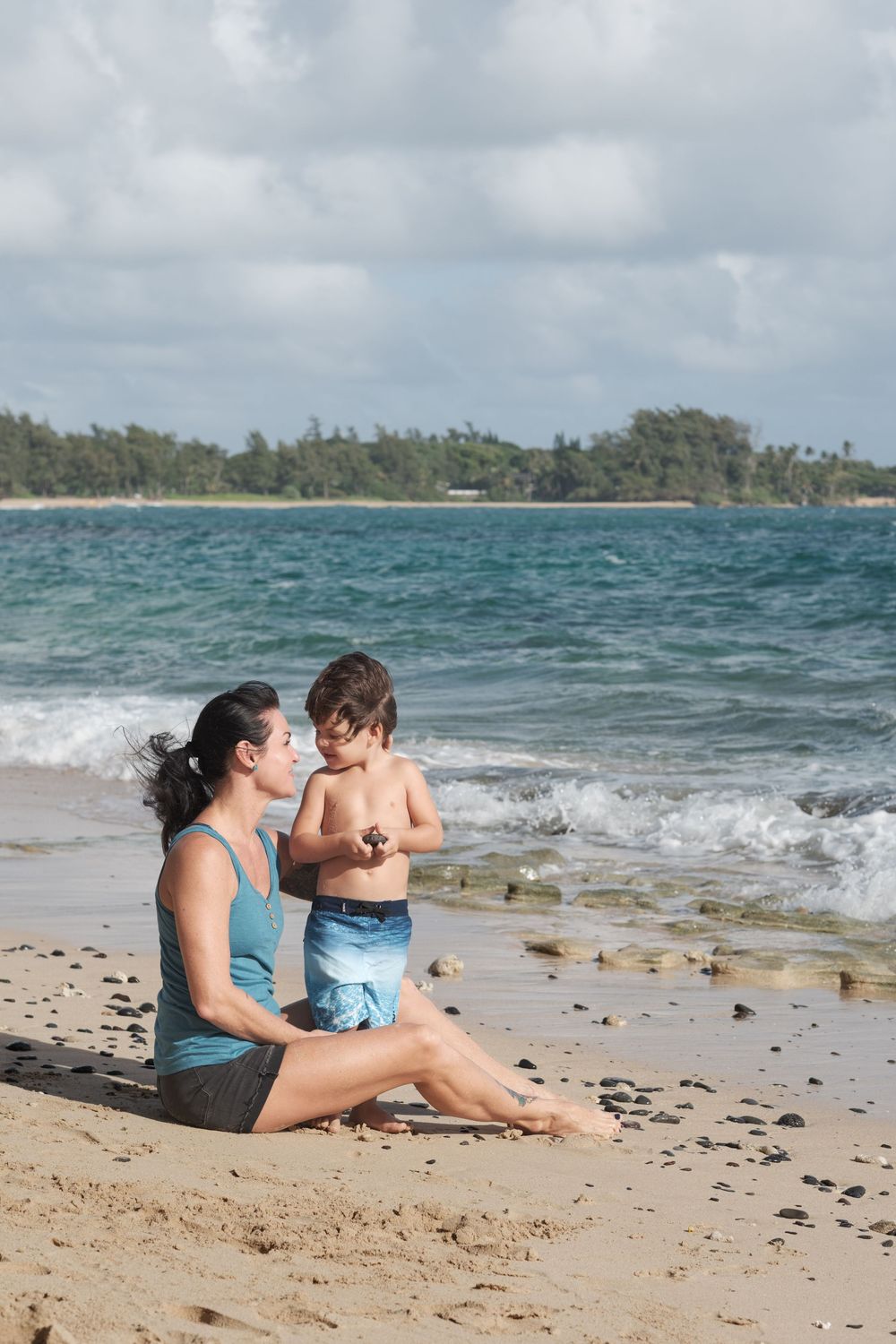 Mother and child sharing a quiet moment during a North Shore Oahu family photography session on a tropical beach.