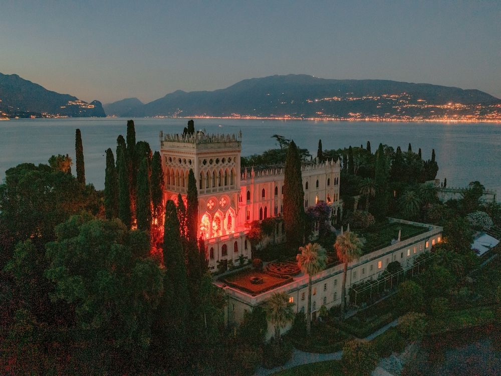 Bride and groom walking in the gardens of Isola del Garda accompanied by a roaming band