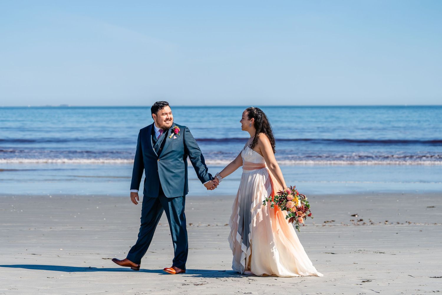 Couple walking on the beach during their wedding portraits in Nahant, Massachusetts.