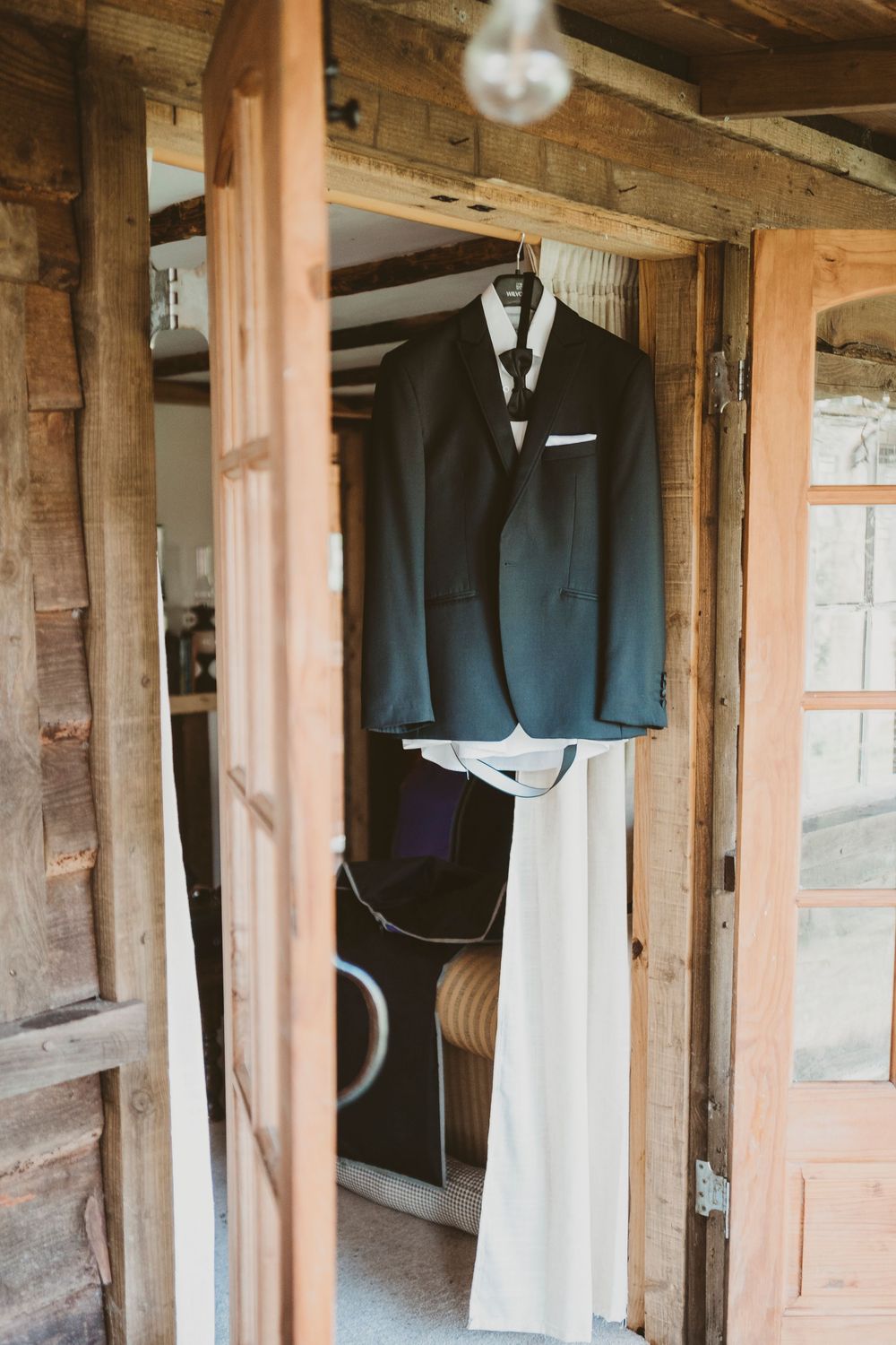 Groom suit hanging in rustic wooden cabin at Parc Le Breos in Gower, West Wales