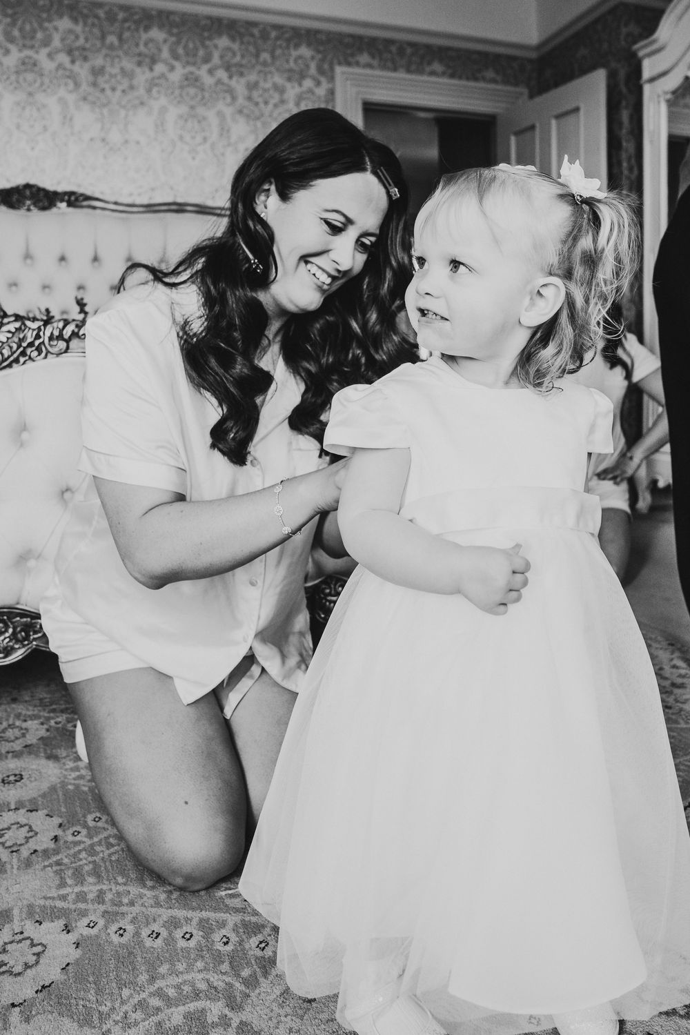 Bride helping flower girl during morning preparations at Parc Le Breos in Gower, West Wales
