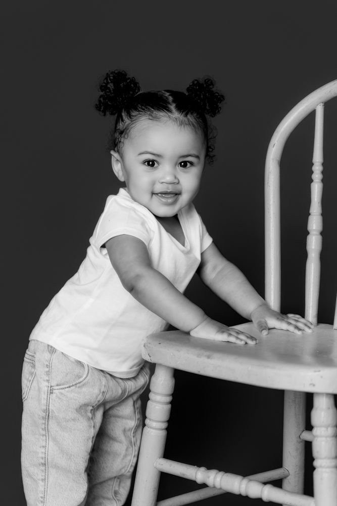 Black and white photo series showing a young child in a white shirt and jeans playing around a white banister.