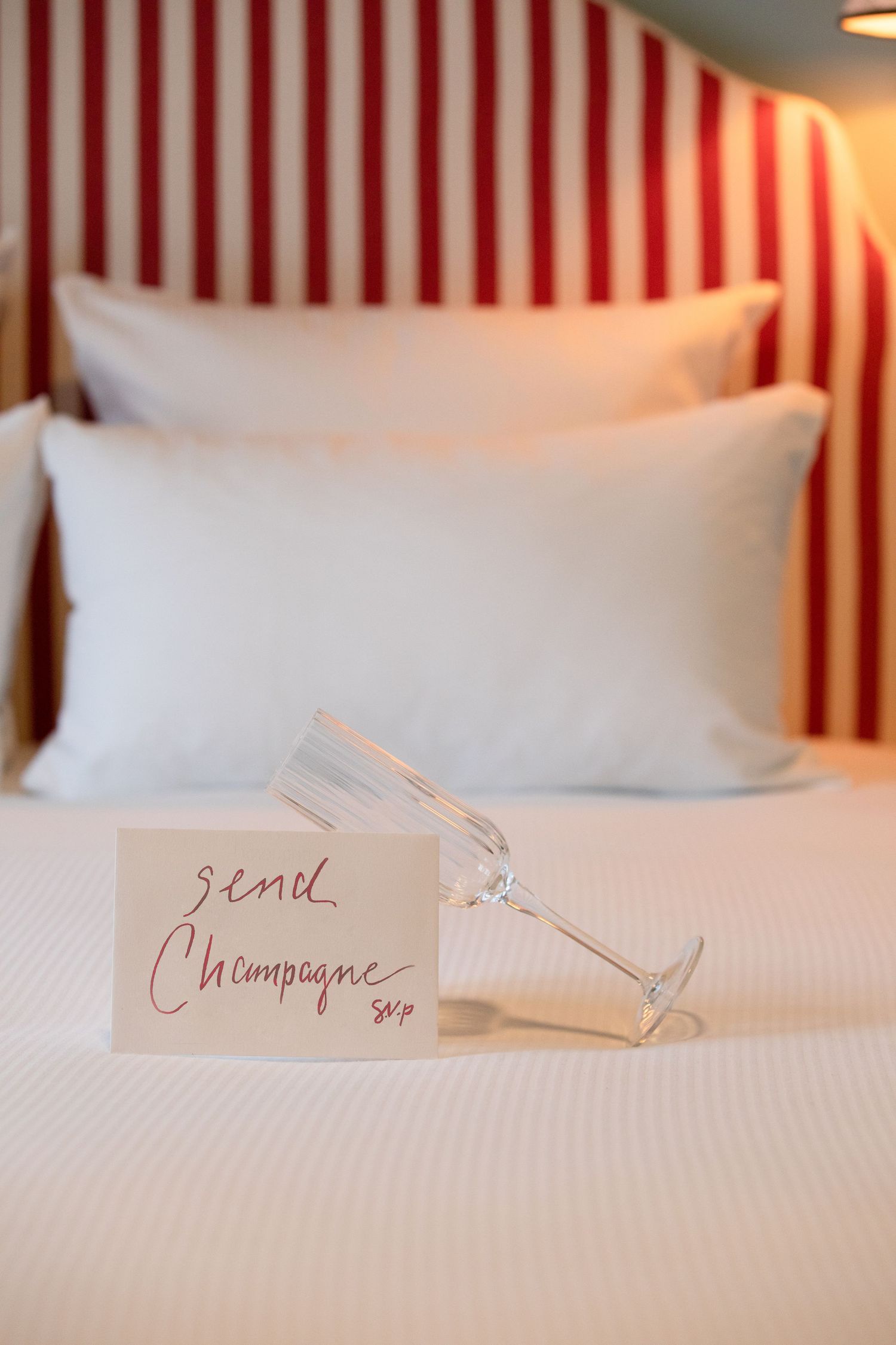 Four close-up shots of white hotel bed linens with handwritten notes and calligraphy details in warm lighting.