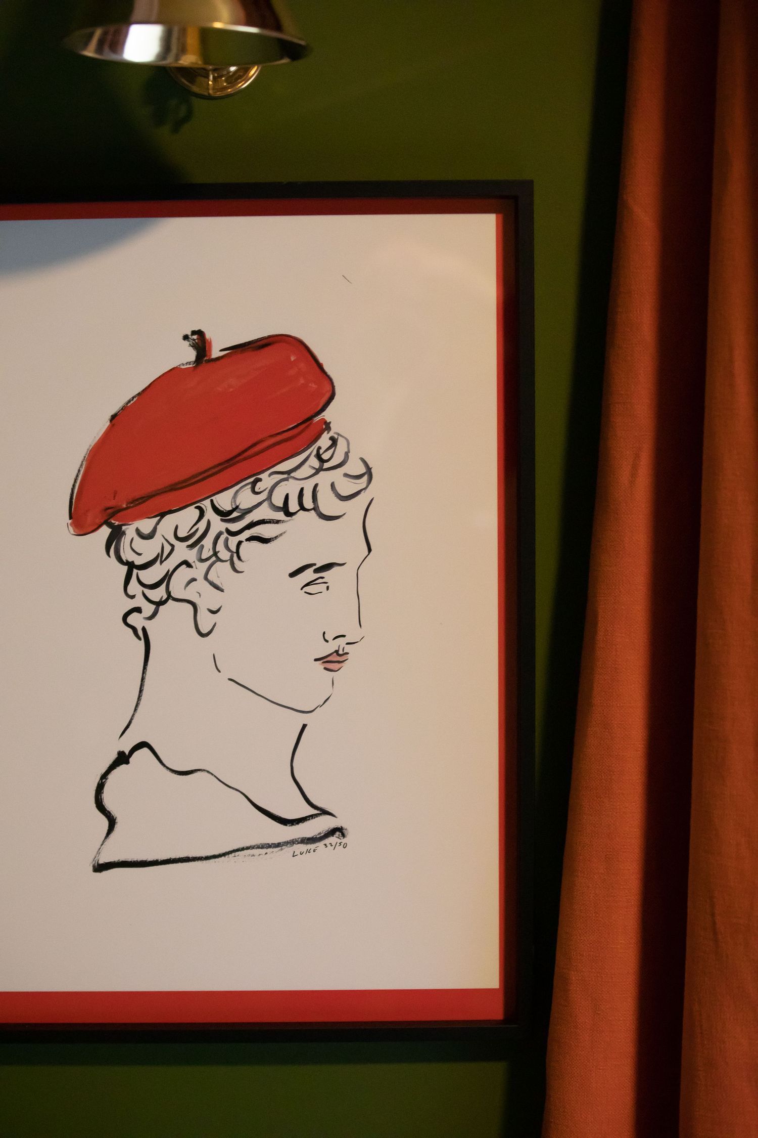A simple line drawing of a figure wearing a red beret, displayed in a frame against a green wall.