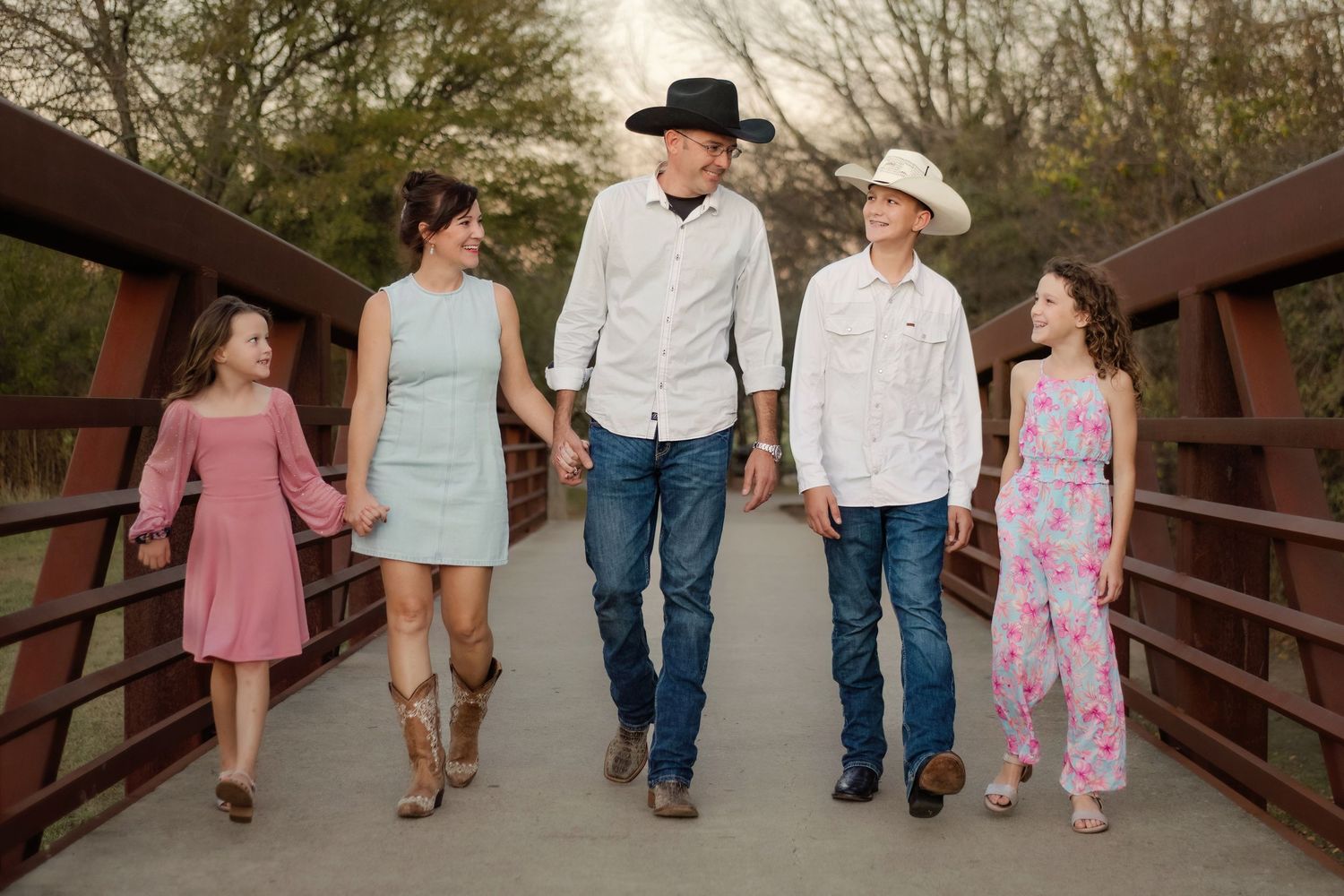 A family walks across a bridge and laughs together during their family session in Keller, TX.