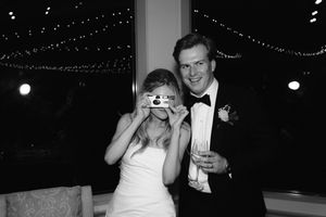 Couple dances together at a wedding reception under twinkling lights and decorative string lighting.