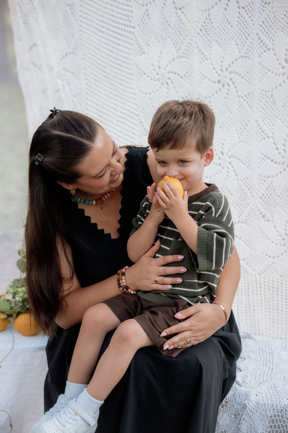 A parent and child share tender moments together against a white lace curtain background.