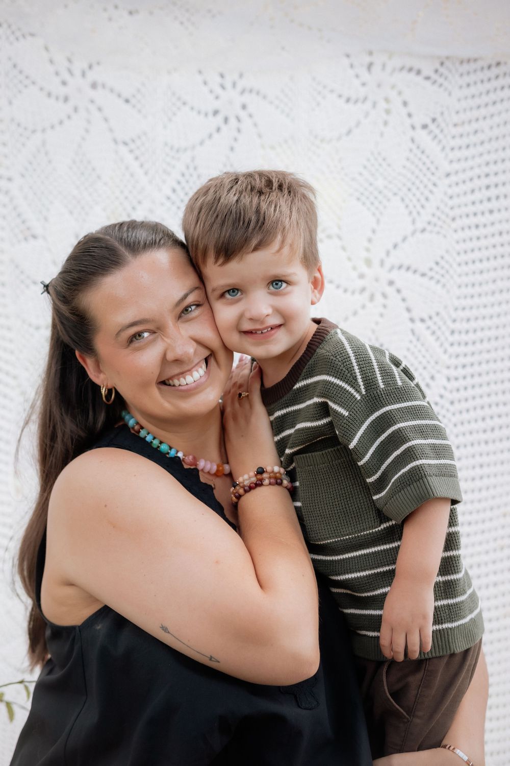 A joyful portrait showing loving affection between parent and child against a white textured background.