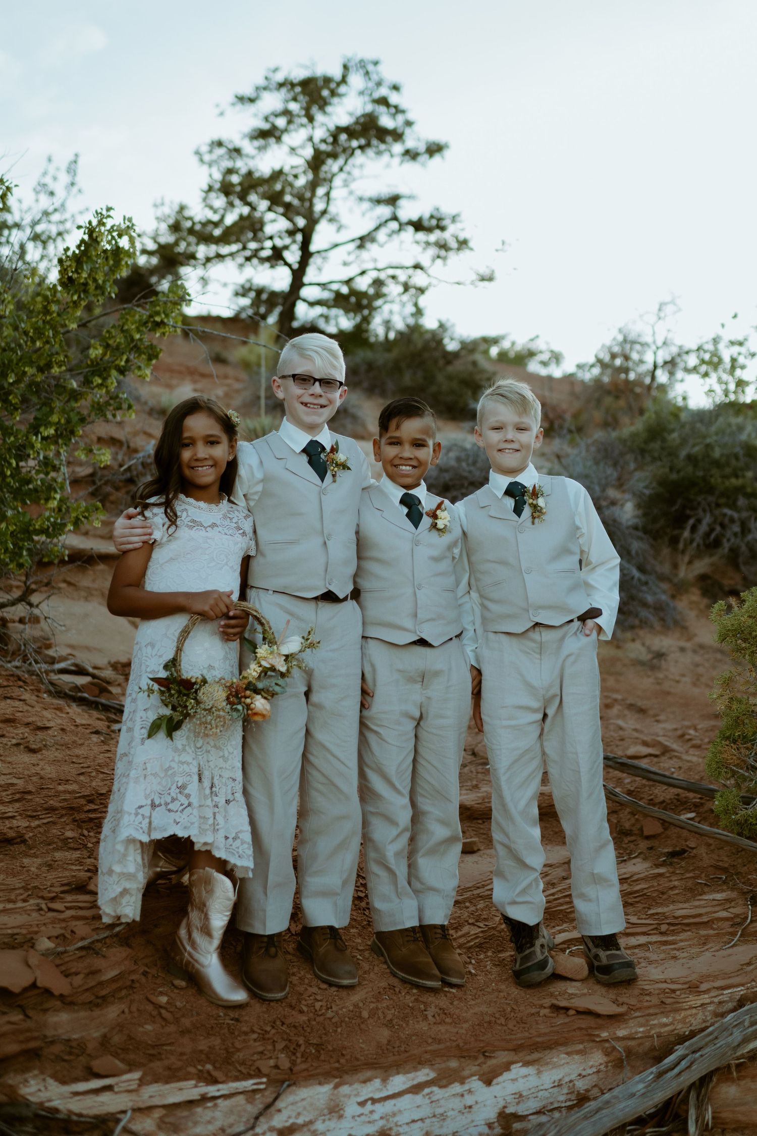Wedding party in white attire posing together on red rock formations.