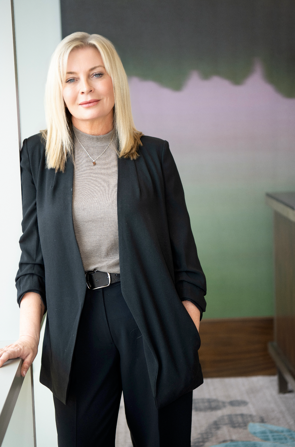 Professional woman in black blazer and beige turtleneck shown in multiple poses against blurred background.