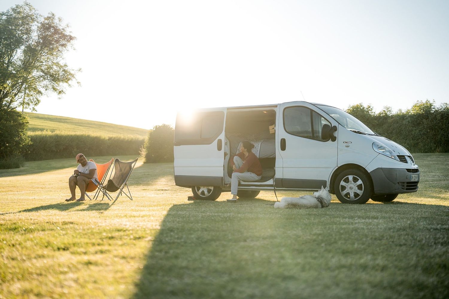 couple en camping en corse avec un van et des transats posés devant avec un chien
