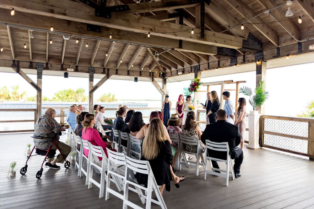 White folding chairs arranged in rows under a rustic wooden pavilion for an outdoor event setup.