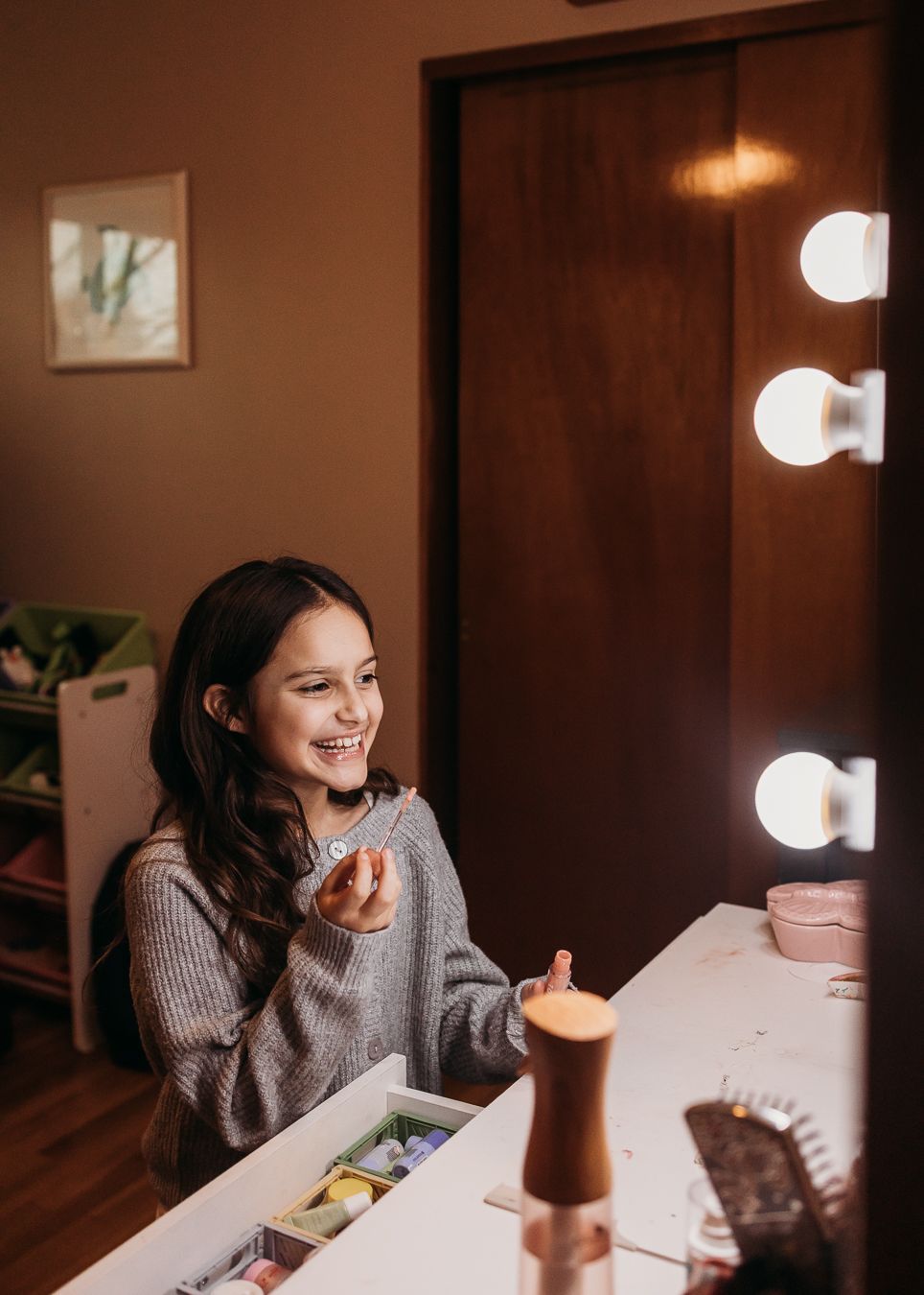 Person sitting at a table in warm lighting while enjoying a beverage and looking down at their phone.