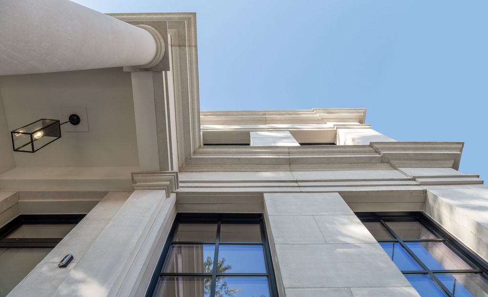 Looking up at modern white apartment buildings with windows and balconies against a blue sky.