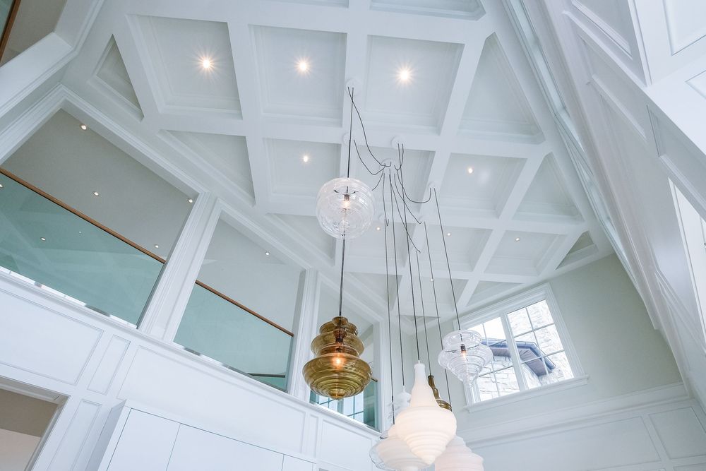 White vaulted ceiling with exposed beams and pendant lights in contemporary architectural design.