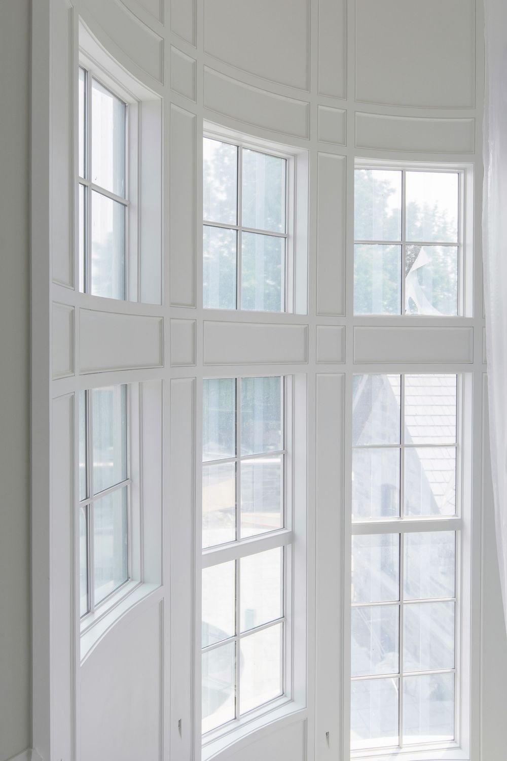 Elegant curved bay window with white trim and multiple glass panes letting in natural light.