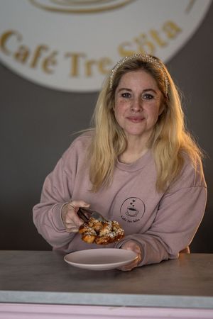 Företagsbilder av Fotograf Jessica Lindqvist - porträtt av ägaren till Cafe Tre Söta på Ingarö, stående vid sin logga.