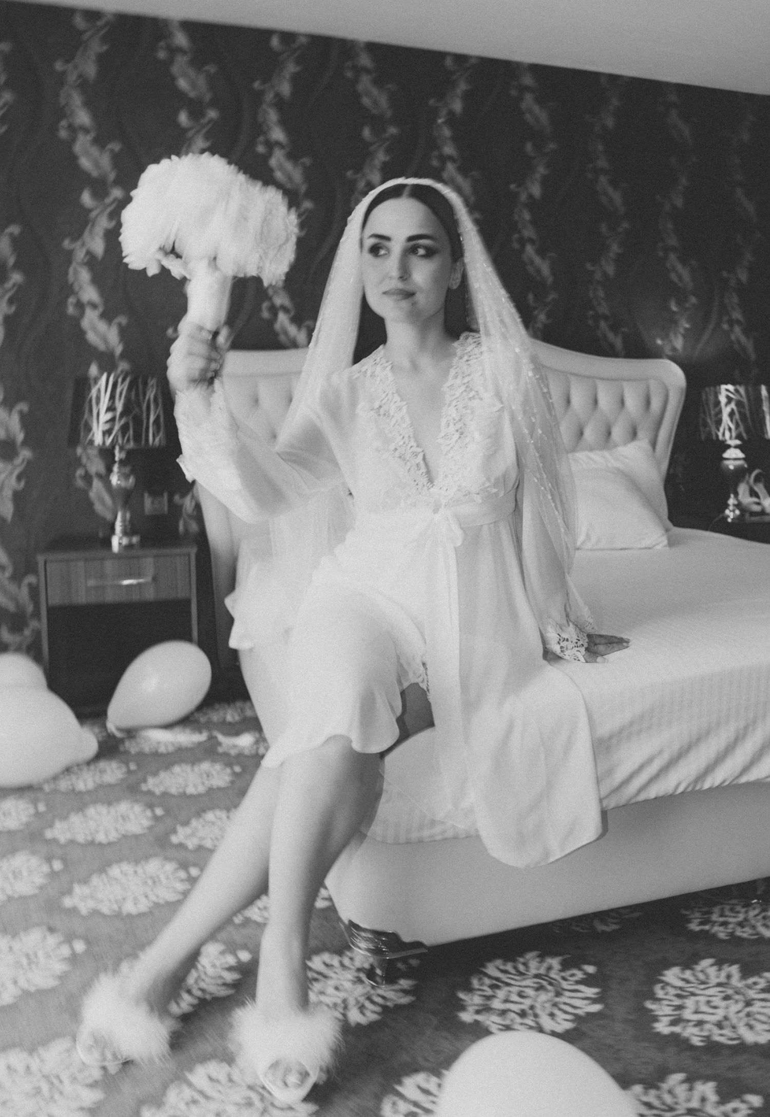 Black and white boudoir photography series showing a woman in white lace lounging on an elegant chaise with vintage decor.