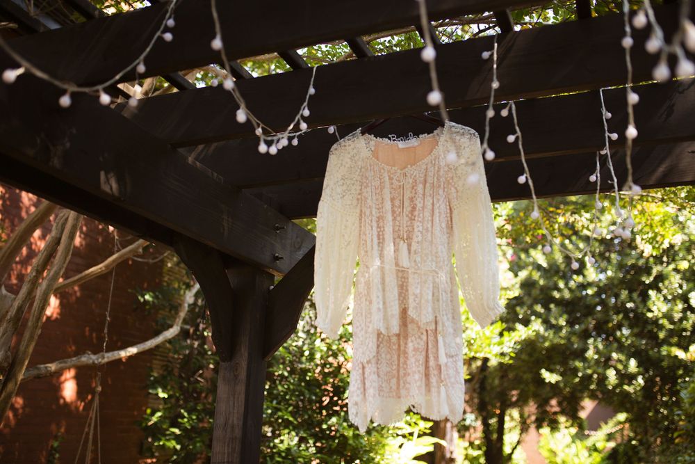 Rustic outdoor wedding decor features hanging white lace dresses and vintage chandeliers creating a dreamy garden atmosphere.