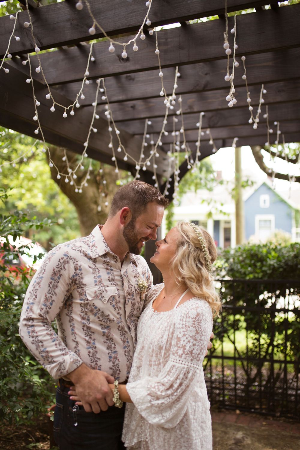 A romantic couple shares tender moments under twinkling string lights in an outdoor garden setting.