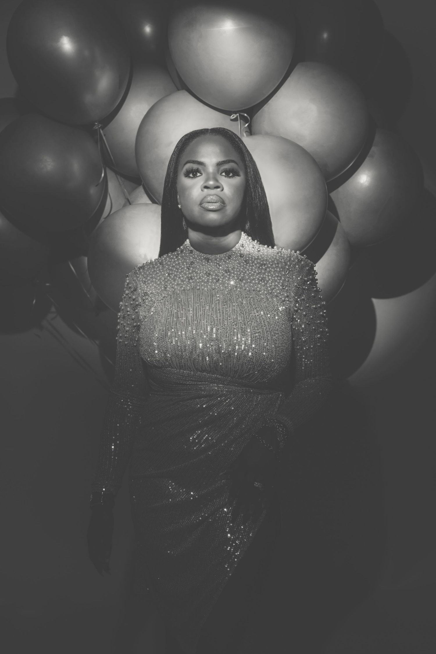 A dramatic black and white portrait with silver balloons and a sparkling dress creates a glamorous atmosphere.