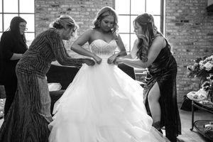 A series of black and white wedding preparation photos showing dress adjustments and final touches before the ceremony.