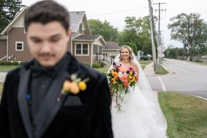 A wedding celebration with guests gathered outdoors near a residential street on a sunny day.