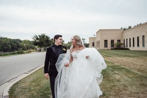A couple celebrates their wedding day outdoors with the bride's dress flowing in the wind.