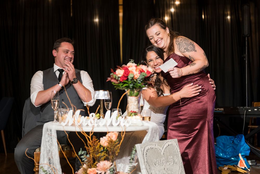 Wedding party seated at decorated tables during evening reception with festive lighting and decor.