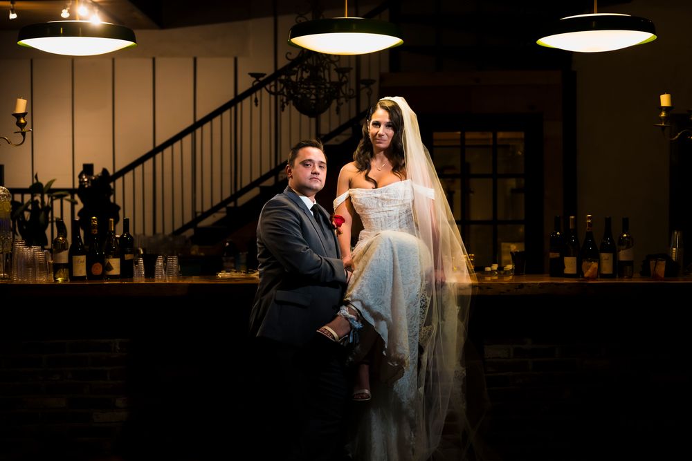 A couple shares a romantic moment under pendant lights during their wedding celebration at an elegant indoor venue.