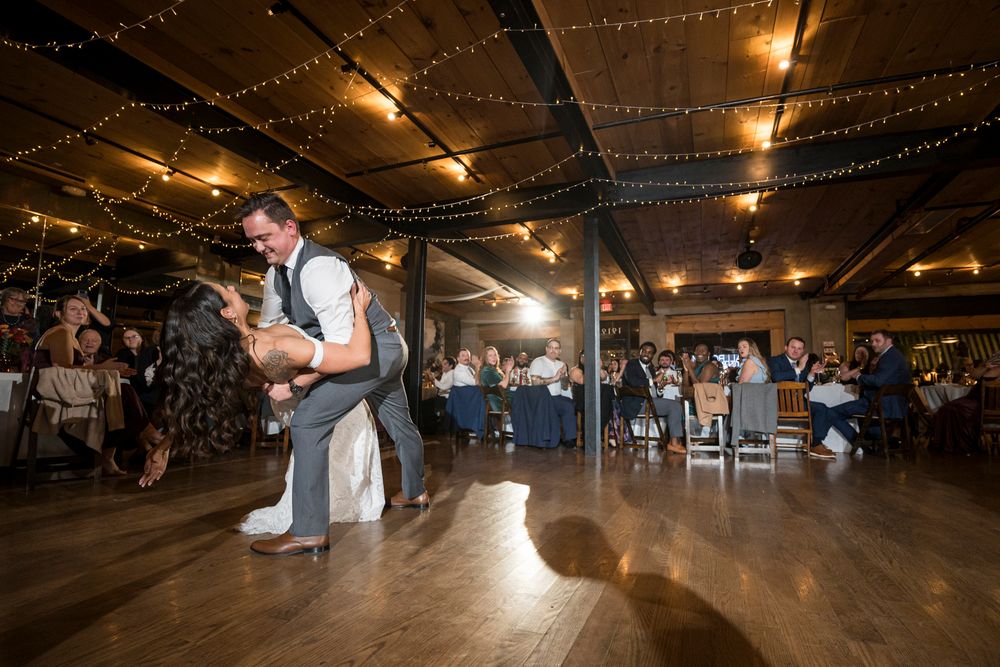 A romantic first dance moment under warm string lights at an indoor wedding reception venue.