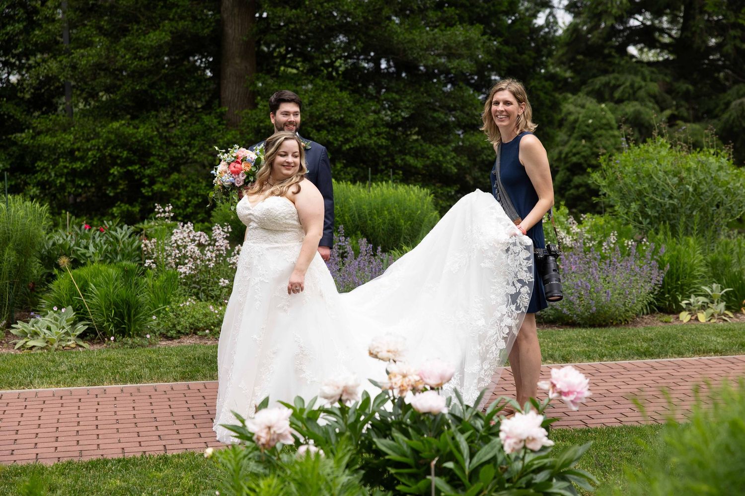 A joyful wedding celebration in a lush garden setting with white flowers and brick pathways.