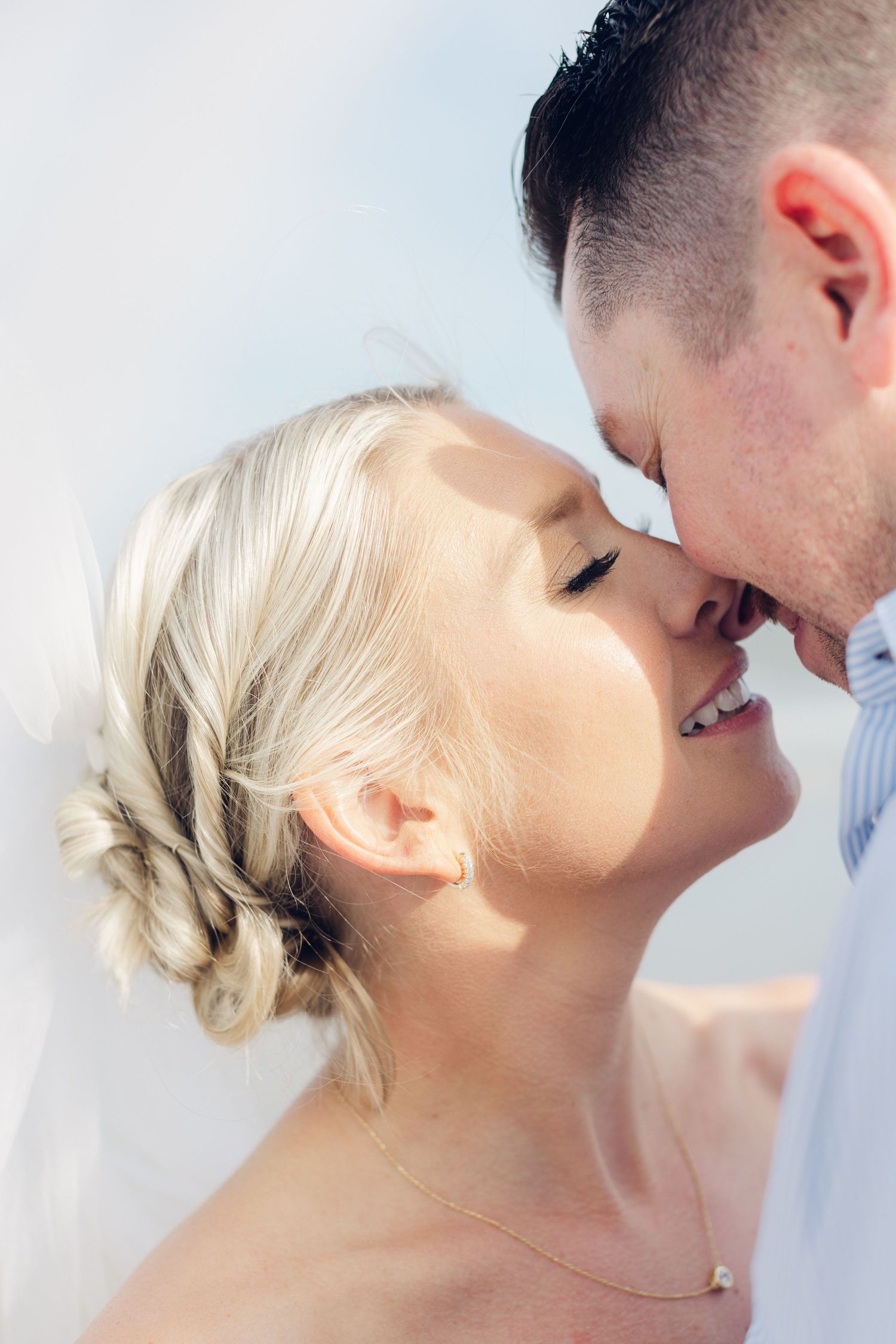 A smiling bride with braided updo shares a tender kiss with groom in soft natural light at elopement on Hunting Island in South Carolina.