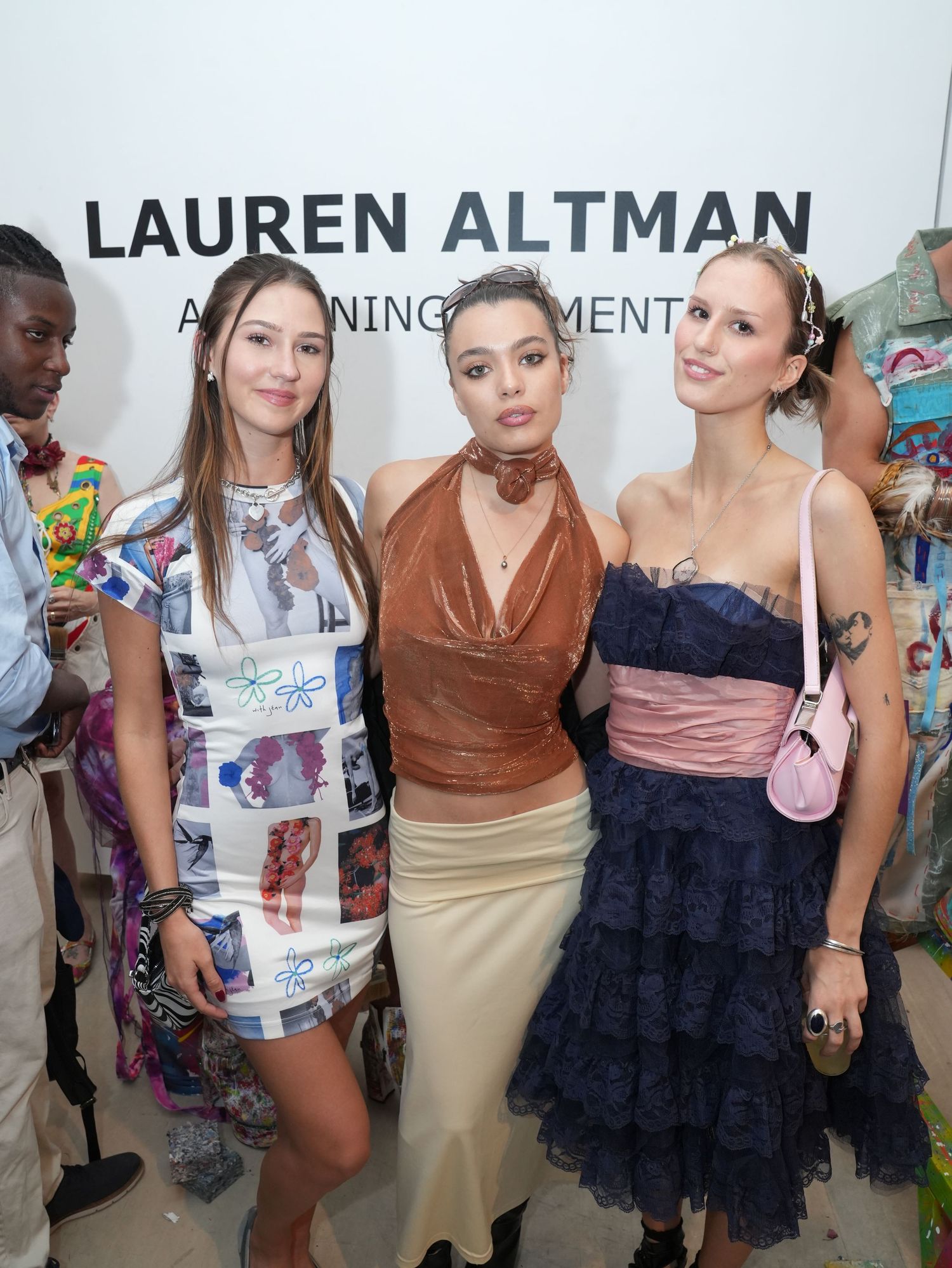 Three stylish women posing together at a Lauren Altman art opening event in trendy outfits.