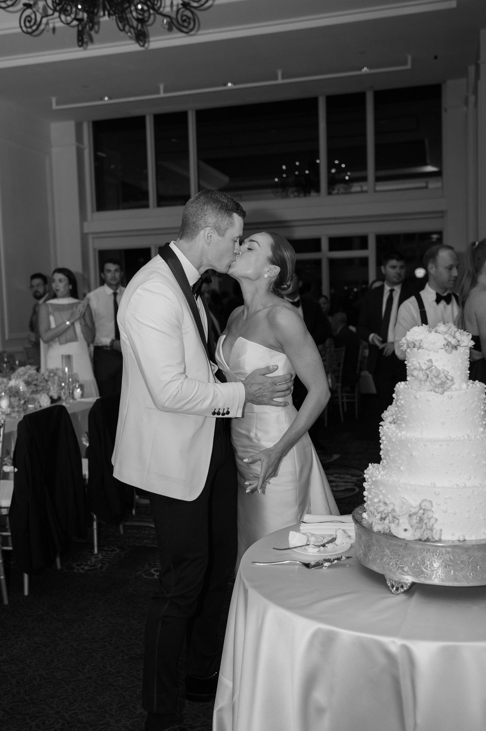 A collage of wedding reception moments showing couples cutting cake and sharing romantic kisses at an elegant venue.